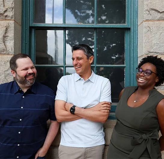Three colleagues standing together outside a blue window