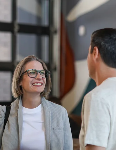 A woman smiling in conversation with a colleague