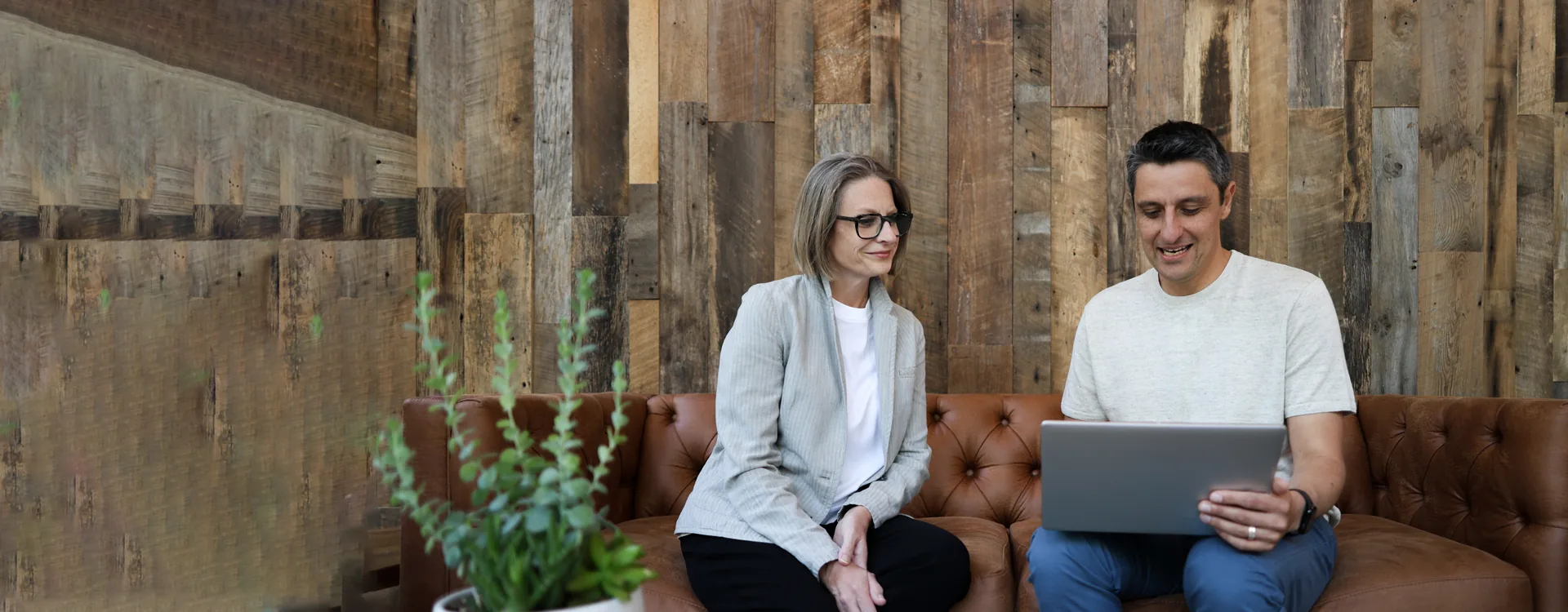 A woman and a man looking at a laptop together on a leather sofa