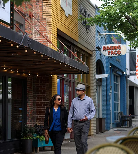 Two people walking past a row of shopfronts