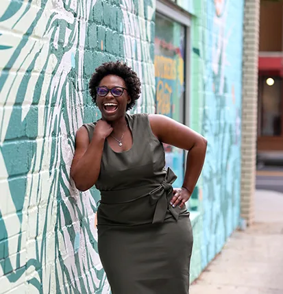 A woman laughing in front of a painted wall
