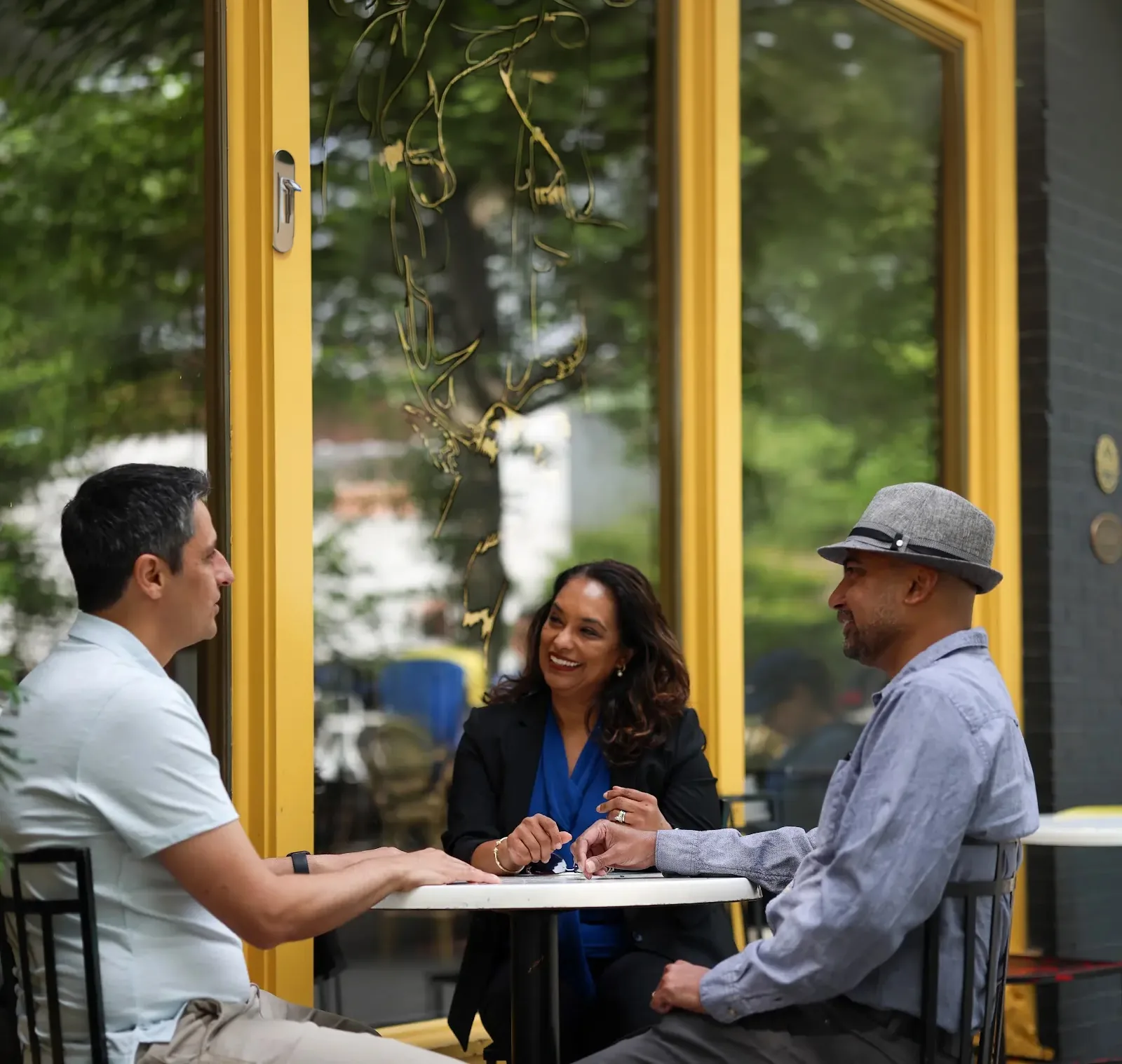 Three people talking around a table outside a cafe