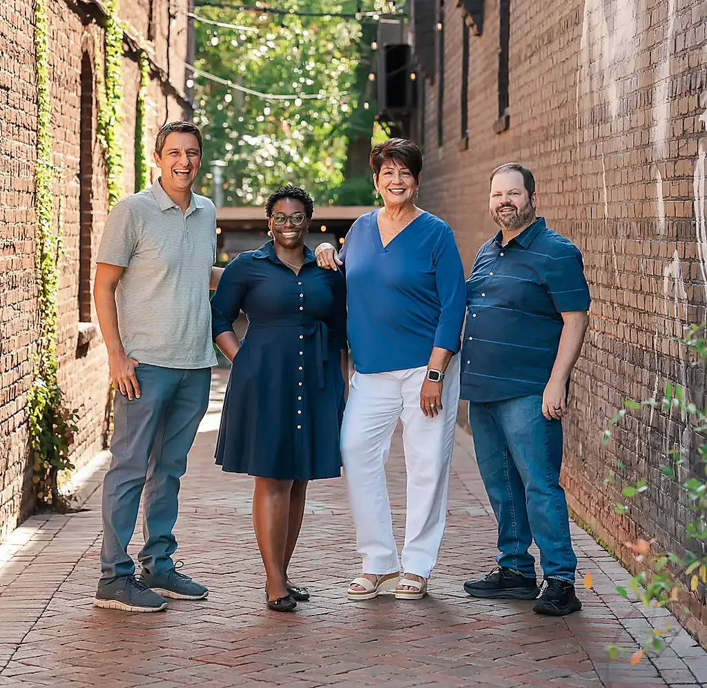 Four colleagues standing together in a brick alley
