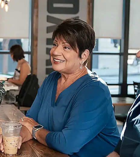 A woman and a man talking at a long table in a coffee shop