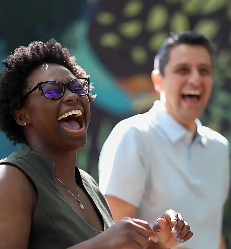 A woman and a man laughing together outdoors